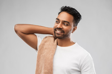 grooming and people concept - smiling indian man with bath towel over grey background