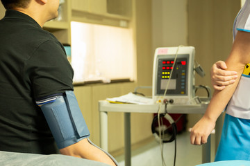 Nurse checking blood pressure on monitor screen for patient health in hospital.