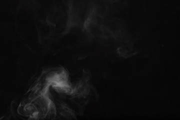 White smoke on a black background. Texture of smoke. Clubs of white smoke on a dark background for an overlay
