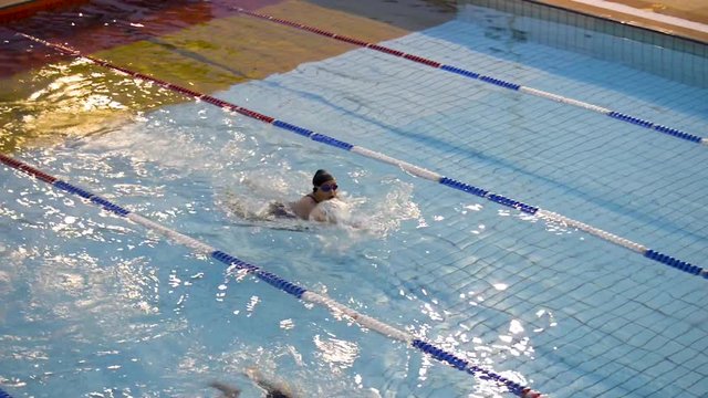 Young man and woman training swiming in olympic pool. Panoramic plane shift