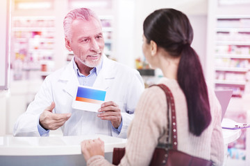 Fototapeta premium Intelligent grey-haired apothecary helping a long-haired customer