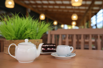Kettle with a drink and dessert in a street cafe. Tea in the kettle cup on the table. Breakfast with tea and cakes at the cafe.