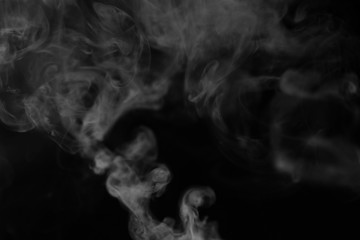 White smoke on a black background. Texture of smoke. Clubs of white smoke on a dark background for an overlay