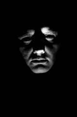 Desaturated man's face illuminated from below with flashlight - obrazy, fototapety, plakaty