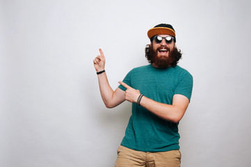 Cheerful man with beard smiling ant pointing away at copyspace