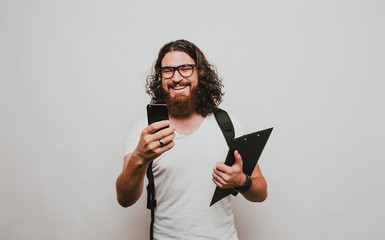 Cheerful bearded man student using phone and smiling