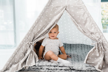 smiling adorable toddler sitting in baby wigwam © LIGHTFIELD STUDIOS