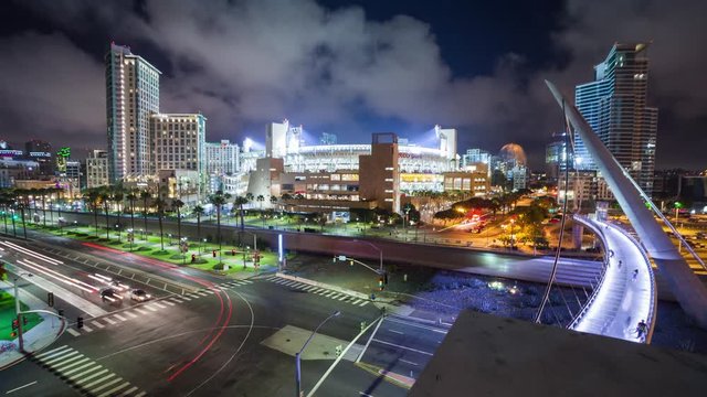 TIMELAPSE: Motion timelpase of Petco Park stadium at night during baseball game. Pedestrians flowing in and out of stadium. Vehicle, train, and trolly traffic are all visable in this shot.