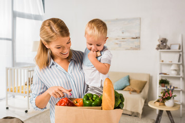 smiling happy mother showing groceries to son