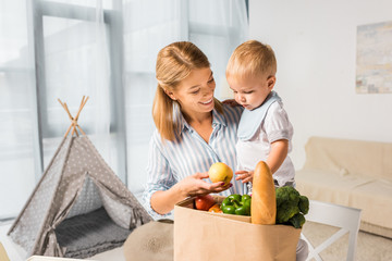 happy mother showing groceries to son with baby wigwam on background © LIGHTFIELD STUDIOS