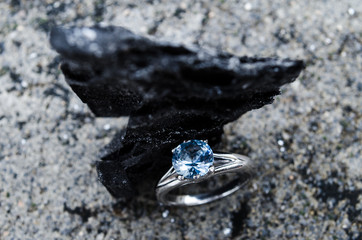 Engagement ring set on a piece of natural charcoal, black carbon texture on jewelry
