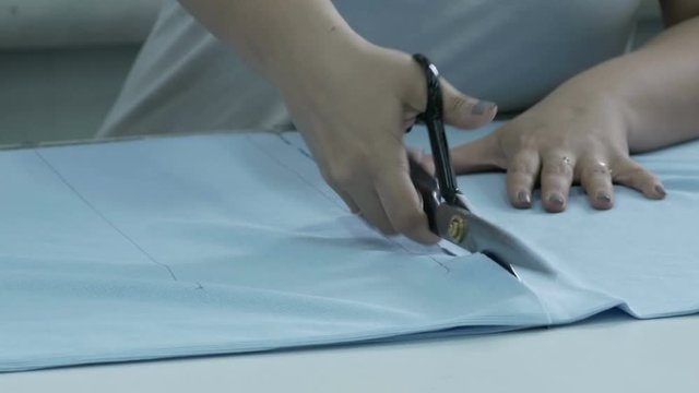 Cutting the fabric, sewing work. Cutting room, cutting blue cloth scissors.