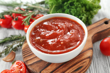 Tasty tomato sauce in bowl on wooden board