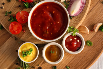 Different tasty sauces in bowls on wooden boards