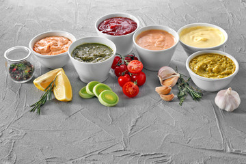 Different tasty sauces in bowls on grey background