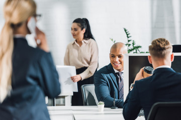 smiling young african american businessman working with colleagues in open space office