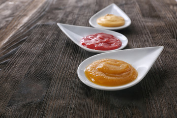Plates with different tasty sauces on wooden table