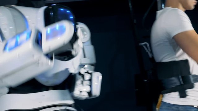 Cyborg is repeating movements after a young man in virtual reality headset