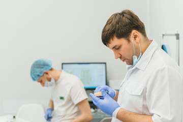 Fototapeta premium Doctor used microscope. Dentist is treating patient in modern dental office. Operation is carried out using cofferdam. Client is inserted and restored teeth, make denture. Orthodontist and assistant