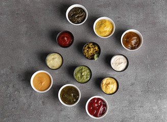 Obraz na płótnie Canvas Different tasty sauces in bowls on grey table