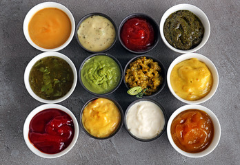 Different tasty sauces in bowls on grey table