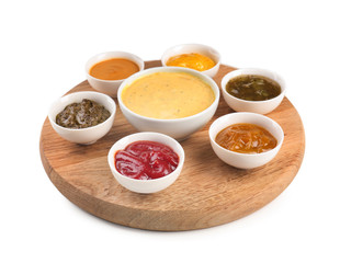 Wooden board with tasty sauces in bowls on white background