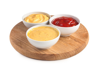 Wooden board with tasty sauces in bowls on white background