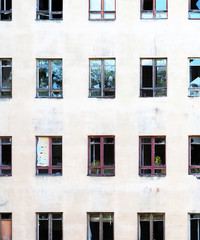 Old and poor facade, front windows of an abandoned building, broken glass. Vertical background