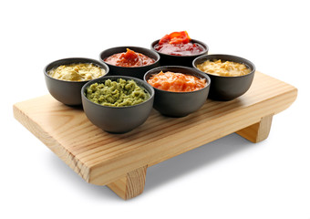 Wooden stand with tasty sauces in bowls on white background