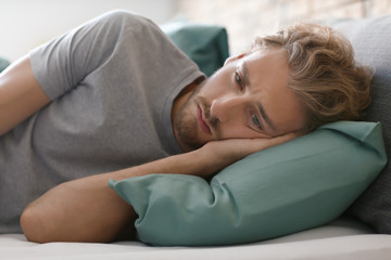Obraz na płótnie Canvas Depressed young man lying in bed
