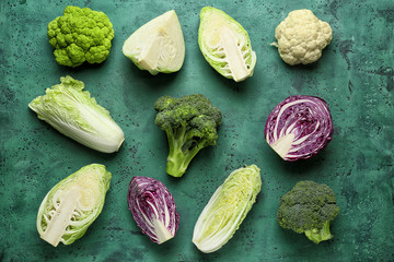 Different kinds of cabbage on color background