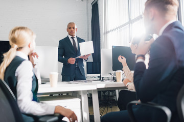 low angle view of young business team looking at african american businessman holding laptop