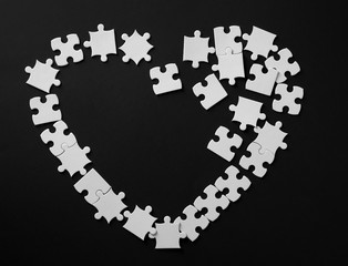 Heart made of jigsaw puzzle pieces on dark background