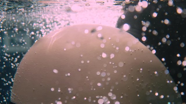 Cinematic shot of a huge belly at forty weeks, before the woman swims away