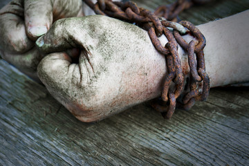 Powerful dirty male hands clenched into fists chained with rusty chain.