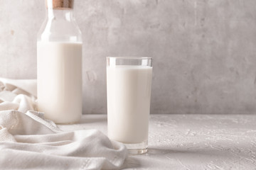 Glass and bottle of tasty milk on white table