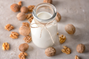 Bottle of tasty milk and walnuts on white table