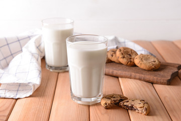 Glasses of tasty milk and cookies on wooden table