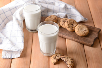 Glasses of tasty milk and cookies on wooden table