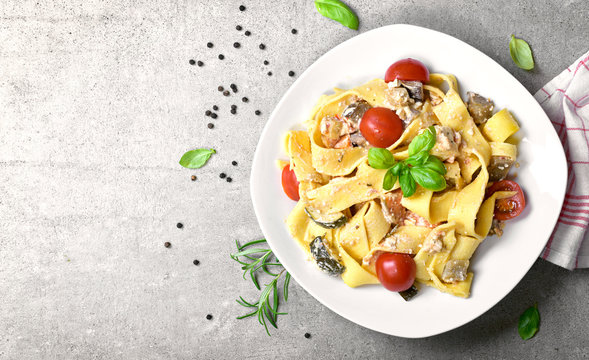 Delicious Pasta Dish With Ricotta Sauce And Fresh Herbs. Tagliatelle Noodles On A White Plate, Italian Cuisine. Top View Or High Angle Shot With Copy Space.