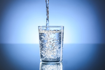 Pouring of water in glass on table