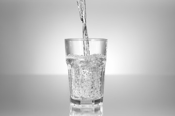 Pouring of water in glass on table