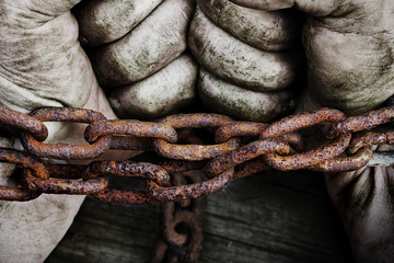 Powerful dirty male hands clenched into fists chained with rusty chain.