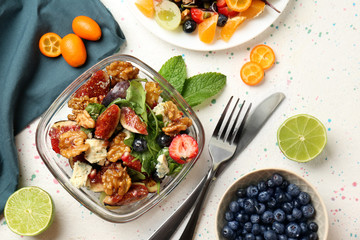 Delicious fresh salad with walnuts in glass bowl on light table