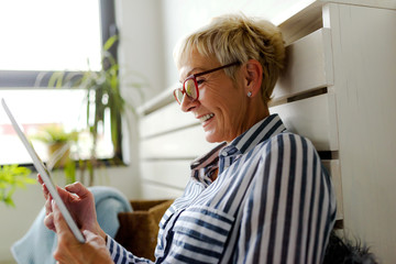 Smiling beautiful senior woman using digital tablet at home