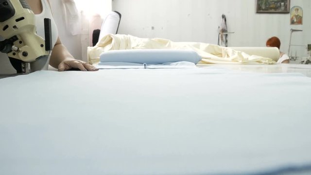 Cutting the fabric, sewing work. Cutting room, woman hands cutting blue cloth tailoring knife.