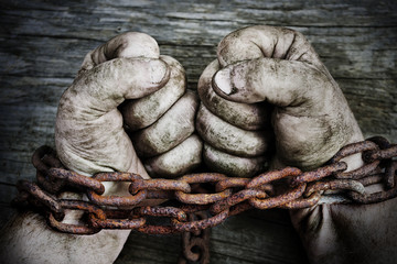 Powerful dirty male hands clenched into fists chained with rusty chain.