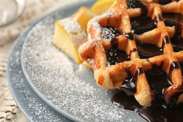 Tasty waffles with chocolate and fruit on plate, closeup