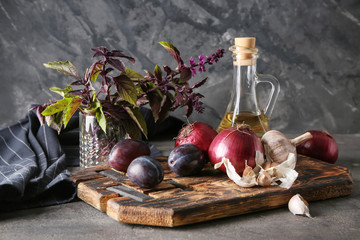 Fresh vegetables with plums on wooden board