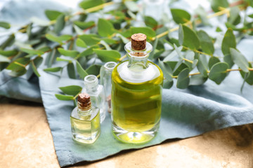 Bottles with essential oil and eucalyptus branches on table